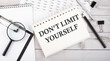 © Iryna - Notepad with text DON'T LIMIT YOURSELF with a pen,office tools and graphs on the desktop.