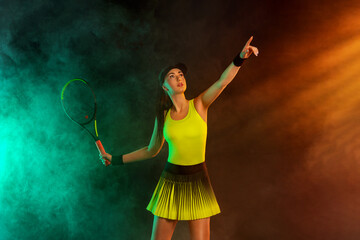 Wall Mural - Tennis player with racket in sportswear. Woman athlete playing dark background.