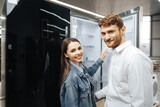 Fototapeta  - Young couple selecting new refrigerator in household appliance store