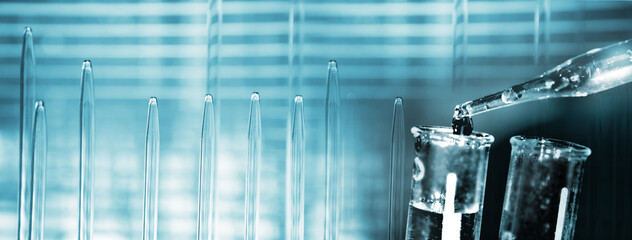 Wall Mural - water from glass dropper or pipette into test tube blue science lab banner background
