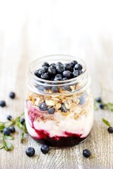 Poster - healthy breakfast in a small jar - blueberries, yogurt, granola, muesli, blueberry berry syrup.