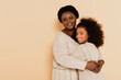 smiling african american grandmother hugging granddaughter on beige background