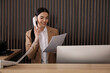 © New Africa - Receptionist with papers talking on phone at countertop in office