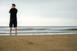 © Steve - A tall Asian man stands on the beach, close-up back view