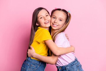 Canvas Print - Portrait of two charming kind cheerful girls wearing casual hugging good mood isolated over pink pastel color background