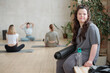 © pressmaster - Young sportswoman with Down syndrome sitting against group of active girls during yoga class