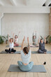 © pressmaster - Back of trainer showing new yoga exercise to group of girls during training