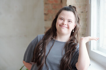 Friendly young brunette female with Down syndrome looking at you with smile