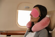 © New Africa - Young woman with travel pillow and mask sleeping in airplane during flight