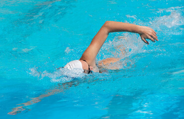 young beautiful woman with swimsuit swimming on a blue water pool