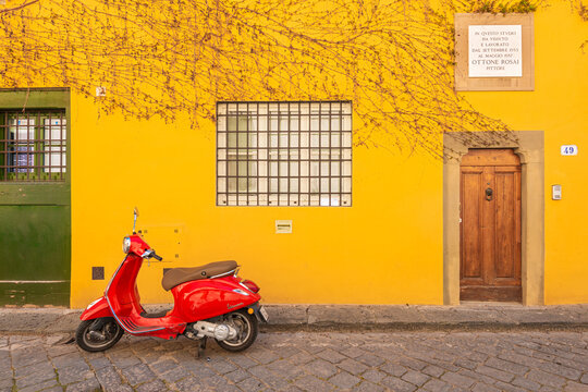 a red italian vespa parked in via san leonardo on the hills of florence