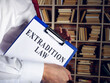 Immigration lawyer holds extradition law with clipboard.