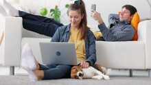 Woman Freelancer Work At Laptop With Dog And Man Browse Internet On Mobile Phone, Lie On Sofa Spbi