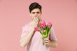 © ViDi Studio - Sick ill allergic man has red eyes runny stuffy sore nose suffer from pollen allergy symptoms hay fever hold blooming flower plant reaction on trigger isolated on pastel pink color background studio.