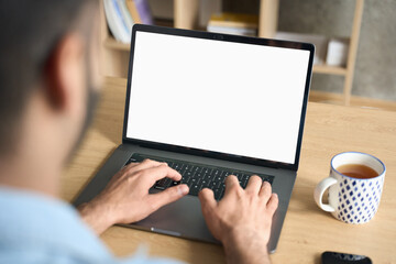 Latin indian adult student typing working remotely online on training educational webinar chatting at home office using laptop computer looking at mockup empty screen. Over shoulder view.