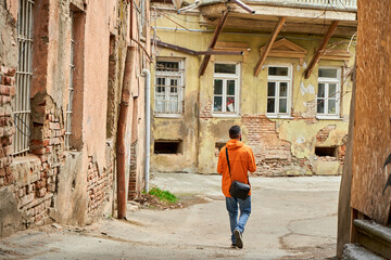 Wall Mural - A lonely guy walks in the old part of the city between dilapidated houses