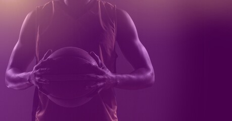 Poster - Composition of fit male basketball player holding ball with copy space on purple background