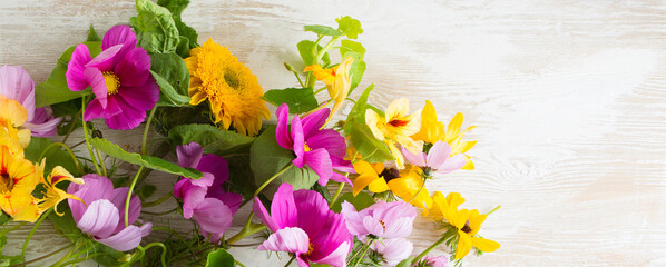 Wall Mural - yellow and purple flowers on a light wooden table, space for text