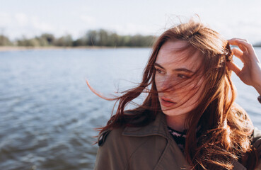 Red hair girl with freckled face outdoors near the lake. Natural beauty, eco lifestyle, nature concept