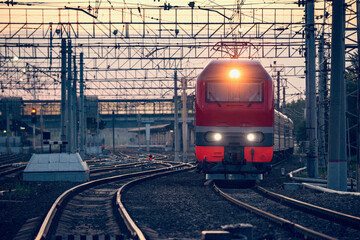 Wall Mural - Passenger train departs from the station at sunset.