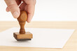 © Formatoriginal - Hand holding a Rubber stamp and blank paper on wooden table. Copy space