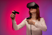 Woman Trying Augmented Reality Glasses, Feeling Excited About VR Headset Simulation And Controllers, Exploring Virtual Life By Gesturing Hands To Touch 3d World, Having Fun With Goggles, On Pink