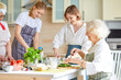 © Roman - Side view on happy senior woman cooking with family, chopping fresh vegetables at Home in cozy kitchen. Children chef in the background. Lifestyle authentic moments. Candid true emotions