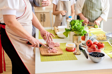 Wall Mural - Close-up photo of table with female hands cutting ingredients for dinner, preparing meal, using cutting board. Food, dinner, meal, cook concept