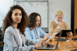 © pressmaster - Attractive businesswoman with laptop sitting by table among co-workers
