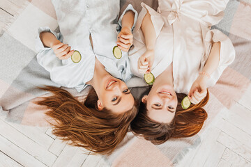 Wall Mural - two girls make homemade face and hair beauty masks. cucumbers for the freshness of the skin around t