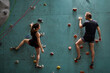Athlete sporty woman and man in sportive outfit practicing rock climbing on artificial rock in sport club. Extreme sports and bouldering concept.
