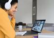 © insta_photos - African American mixed race adult student wearing headphones having virtual meeting online call with teacher, educational webinar chatting at home office. Video e learning conference call on pc.