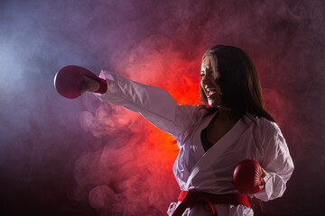 Wall Mural - girl exercising karate punch against red fog background.