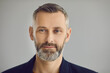 © Studio Romantic - Portrait of confident attractive senior European business man looking at camera with friendly face expression on gray studio background. Head shot of happy mature bank client or barbershop customer
