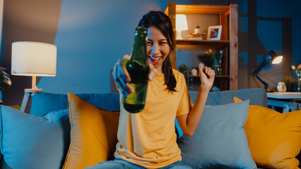 Canvas Print - Happy young asian woman looking at camera enjoy night party event online with friends toast drink beer via video call online in living room at home, Stay at home quarantine, Social distancing concept.