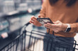 © oatawa - Woman doing grocery shopping at the supermarket, She using shopping cart and connecting with her smartphone, apps and retail concept.