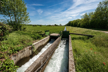 Two small concrete irrigation canals in a rural scene, Padan Plain or Po valley (Pianura Padana, Italian). Mantua province, Italy, southern Europe.