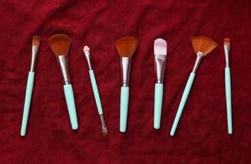 Makeup brushes on red silk background. Beauty still life.