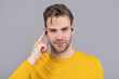 Handsome guy point finger at bluetooth earbud headphones inside ear grey background, listening