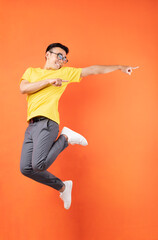 Sticker - Asian man in yellow t-shirt jumping on orange background