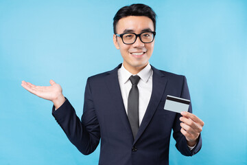 Asian businessman holding bank card on blue background