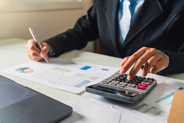 Fototapete - Woman accountant use calculator and computer with holding pen on desk in office. finance and accounting concept