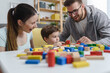 © lordn - Mother and father playing with their cute smart toddler son at home using colorful wooden toys