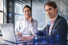 Businessman And Businesswoman Working Together To Protect Clients Confidential Information And Cyber Security. IT Hologram Padlock Icons Over Office Background With Panoramic Windows.