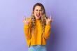 © luismolinero - Young Brazilian woman isolated on purple background making horn gesture