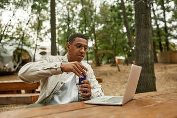 Happy young african american man opening can with drink