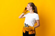 © luismolinero - Young electrician woman isolated on yellow background holding coffee to take away and a mobile
