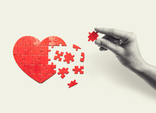 Heart-shaped Puzzle And Human Hand With The Missing Piece Of Puzzle. Love Relationships Concept.