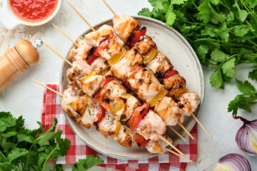 Wall Mural - Chicken shish kebab or skewers kebab in a ceramic plate, spices, cilantro herbs and vegetables on white table background. Barbecue Raw ingredients for goulash or shish kebab. Top view. Free copy space