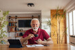 © bnenin - Happy senior man, working from home office, drinking coffee.